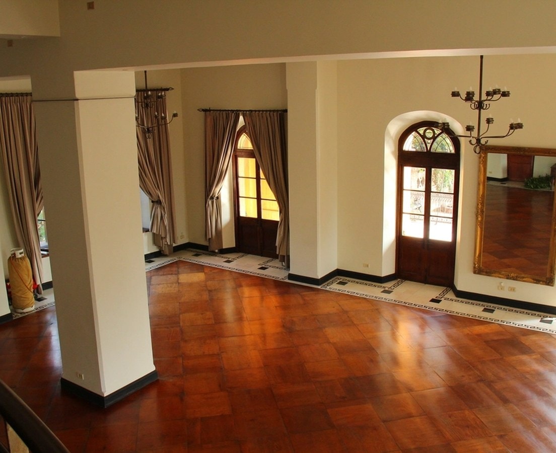 Empty room with a polished wood floor and a tile border, ready for furniture