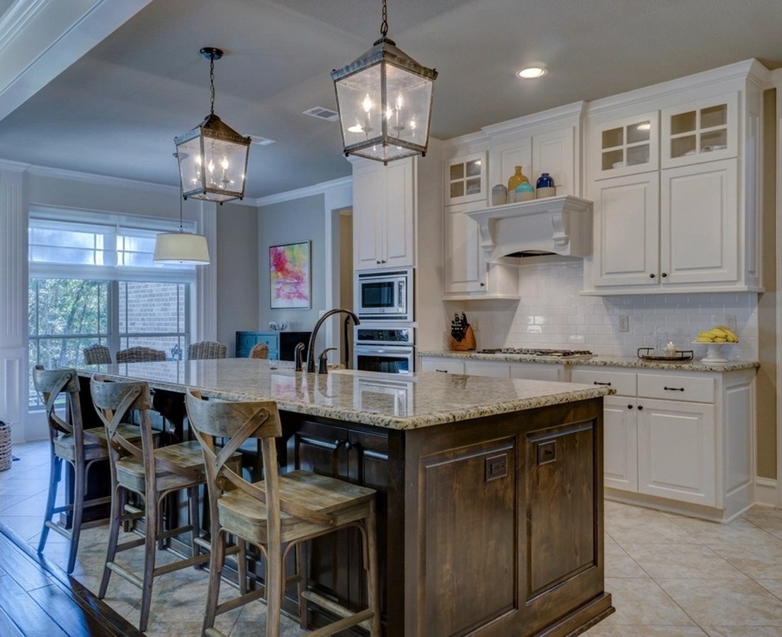 White kitchen with a stained wood island, lantern pendants, and counter seating