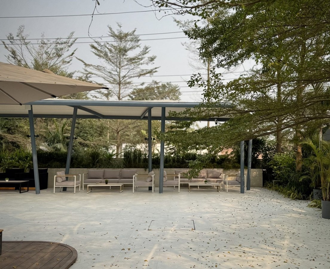 Covered patio pavilion with lounge seating on a tiled terrace among palms