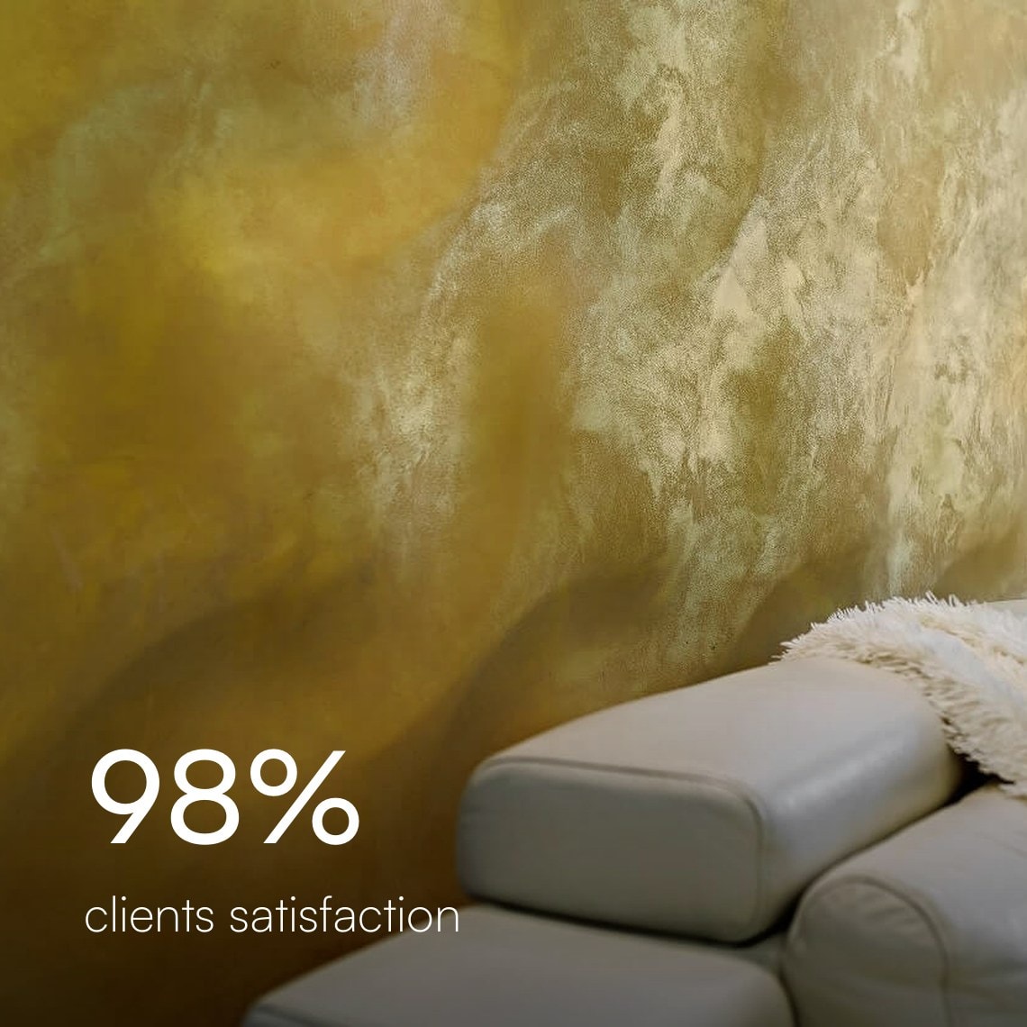 Gold Venetian plaster wall behind a white leather sofa, 98% client satisfaction