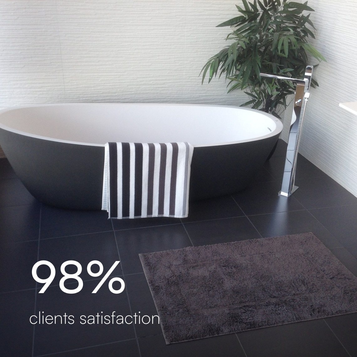 Freestanding black tub with a floor-mounted chrome tub filler on dark tile, 98% client satisfaction