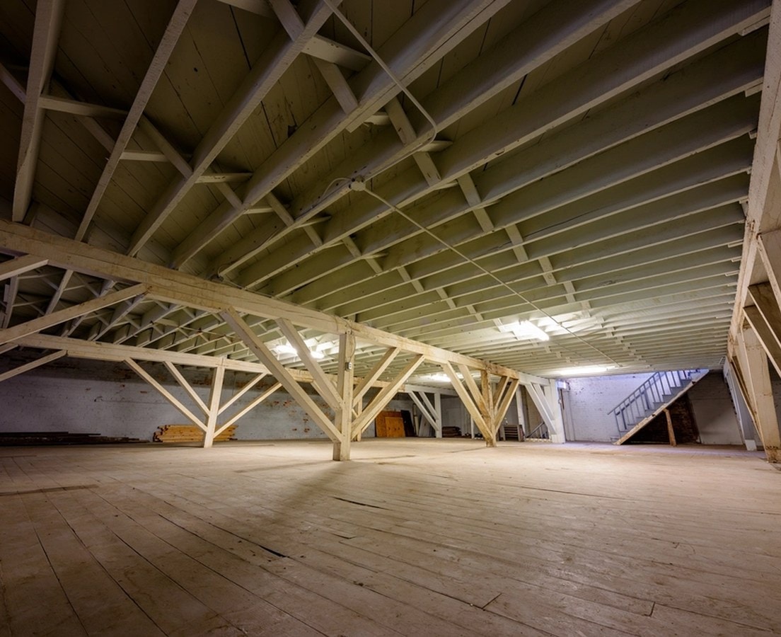Original roof framing and trusses exposed above an empty upper floor