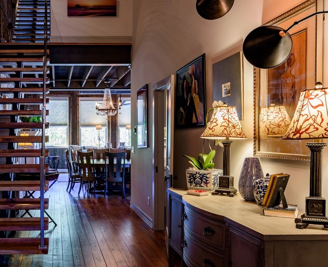Finished hallway with an open stair, lamp-lit console, and a view through to the dining room